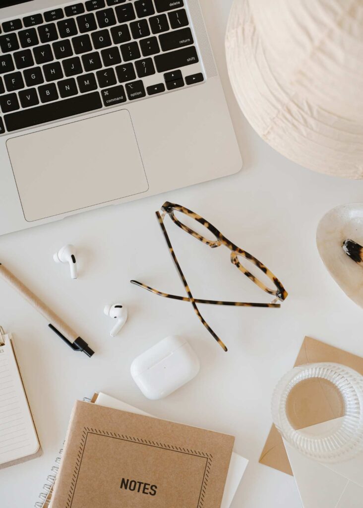 Flat lay of creative business tools including a notebook, coffee cup, and laptop, representing finding your ideal client in a creative business.