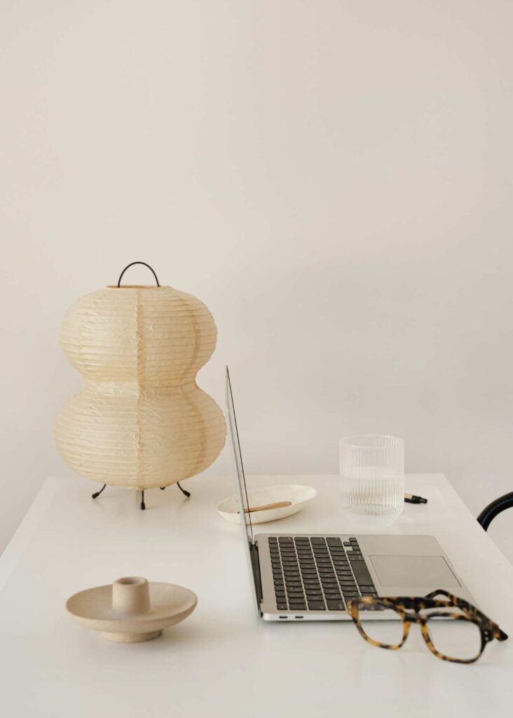 Minimalist workspace setup with a laptop, tortoiseshell glasses, and neutral-toned decor, symbolizing creativity and focus for female small business owners. Ideal for discussing branding, client connections, or business strategies